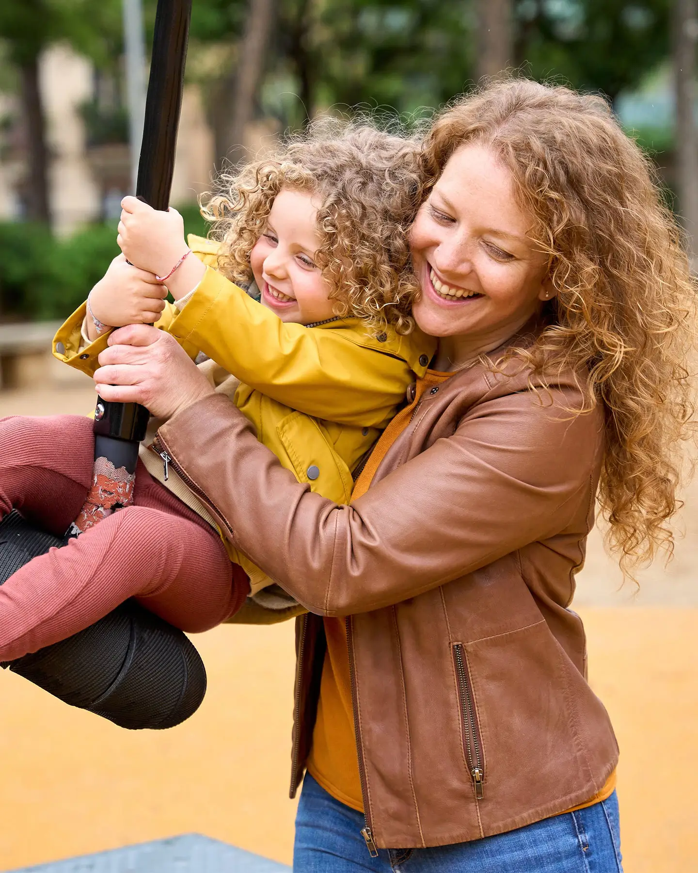 A mother pushing her child on a swing